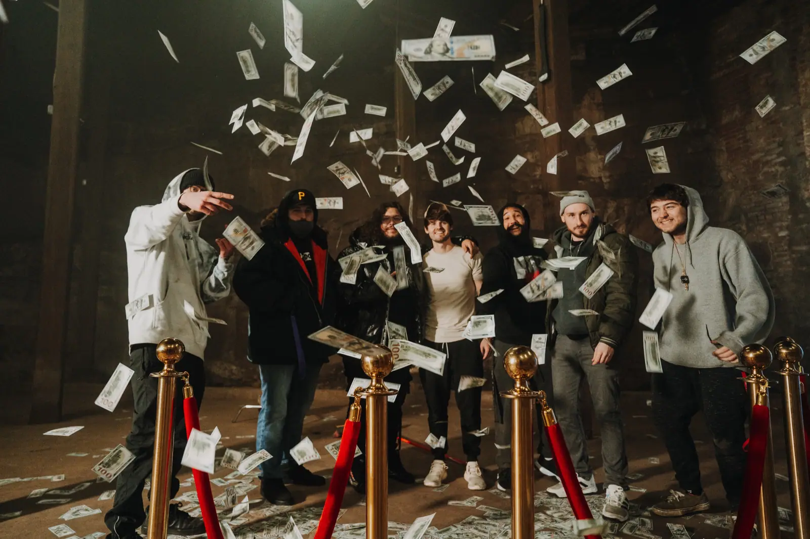 Cast and crew under a shower of prop money in a brick warehouse