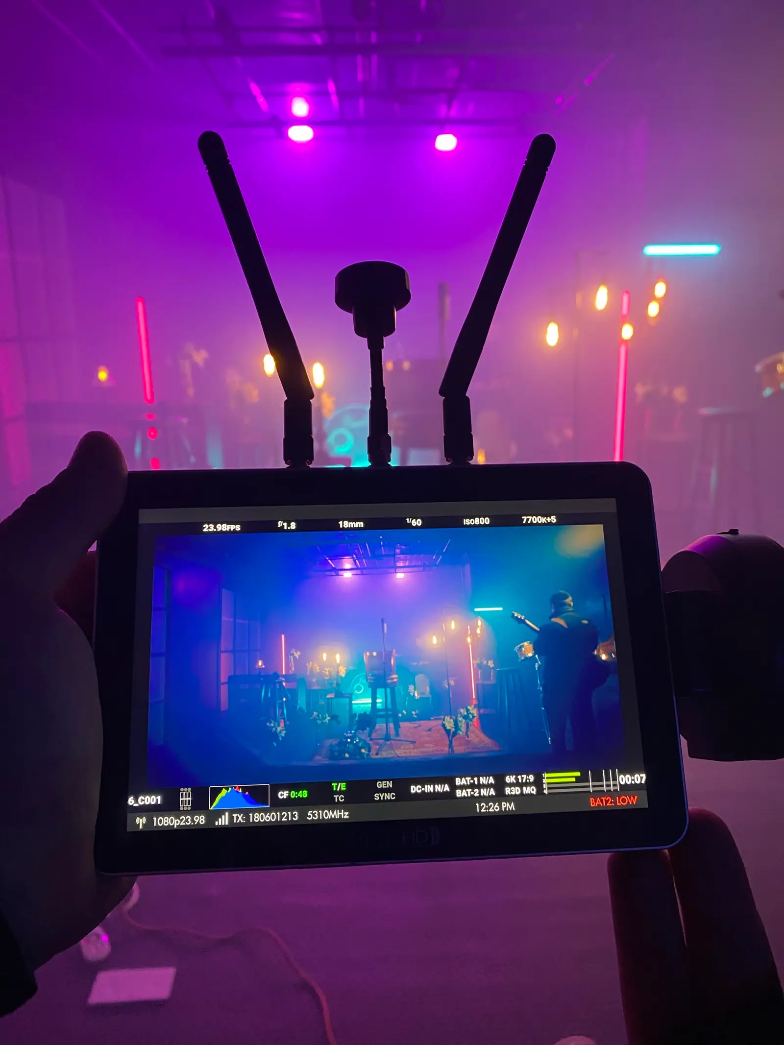 A wireless monitor in hand, the band set glowing purple beyond it