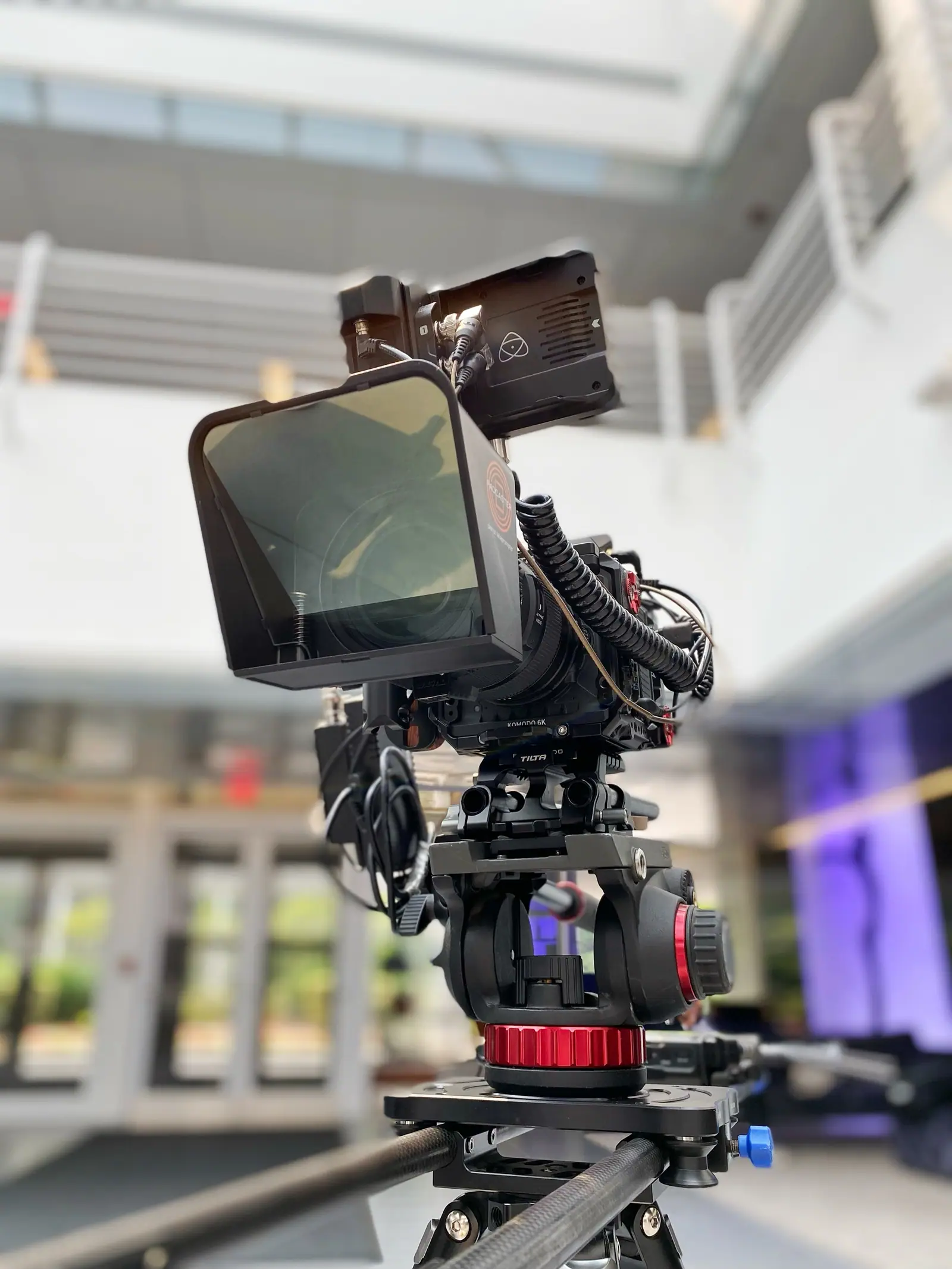 A cinema camera on a fluid head in a bright atrium