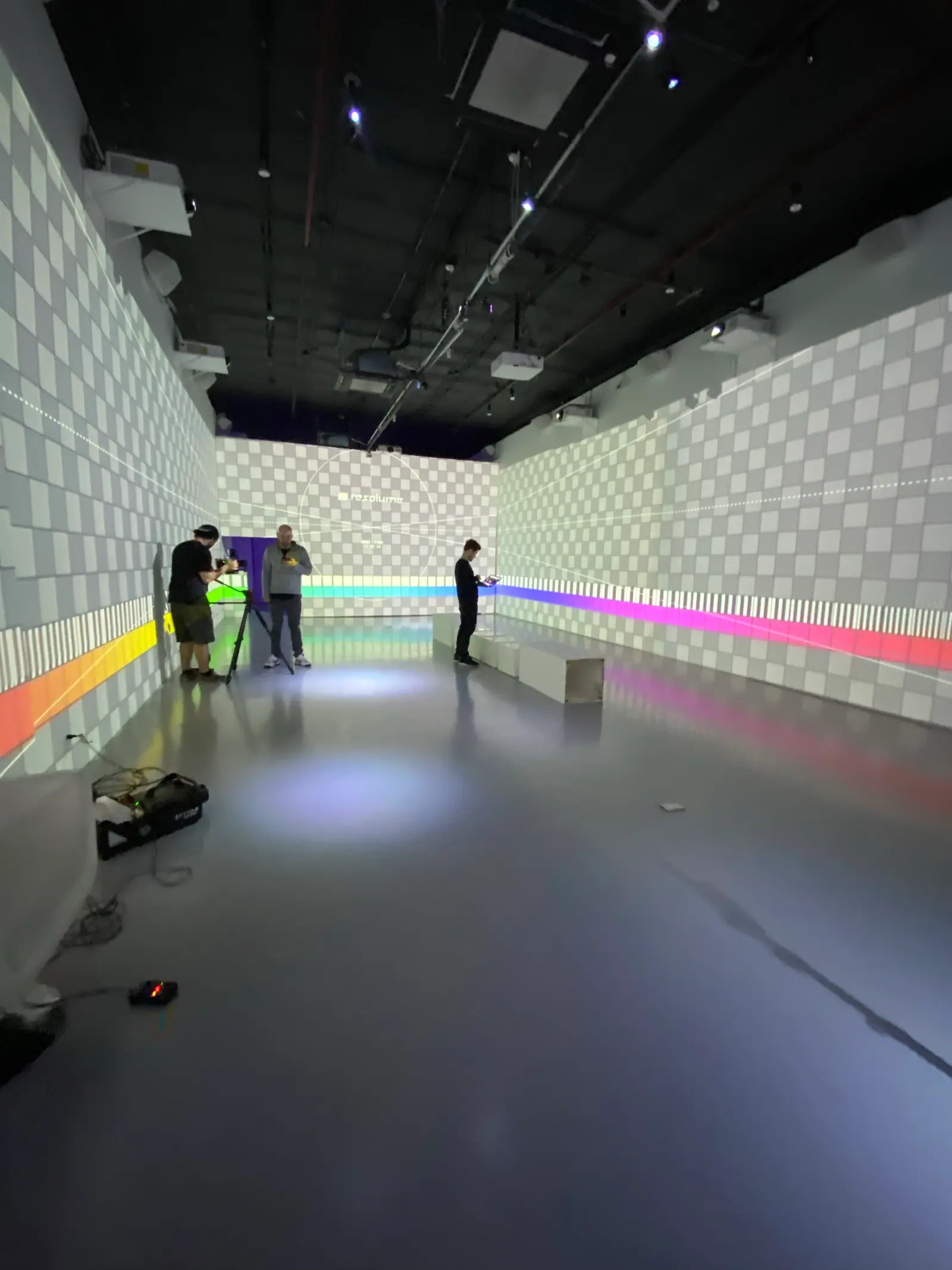 Crew setting up a camera in a long room lined with checkerboard walls